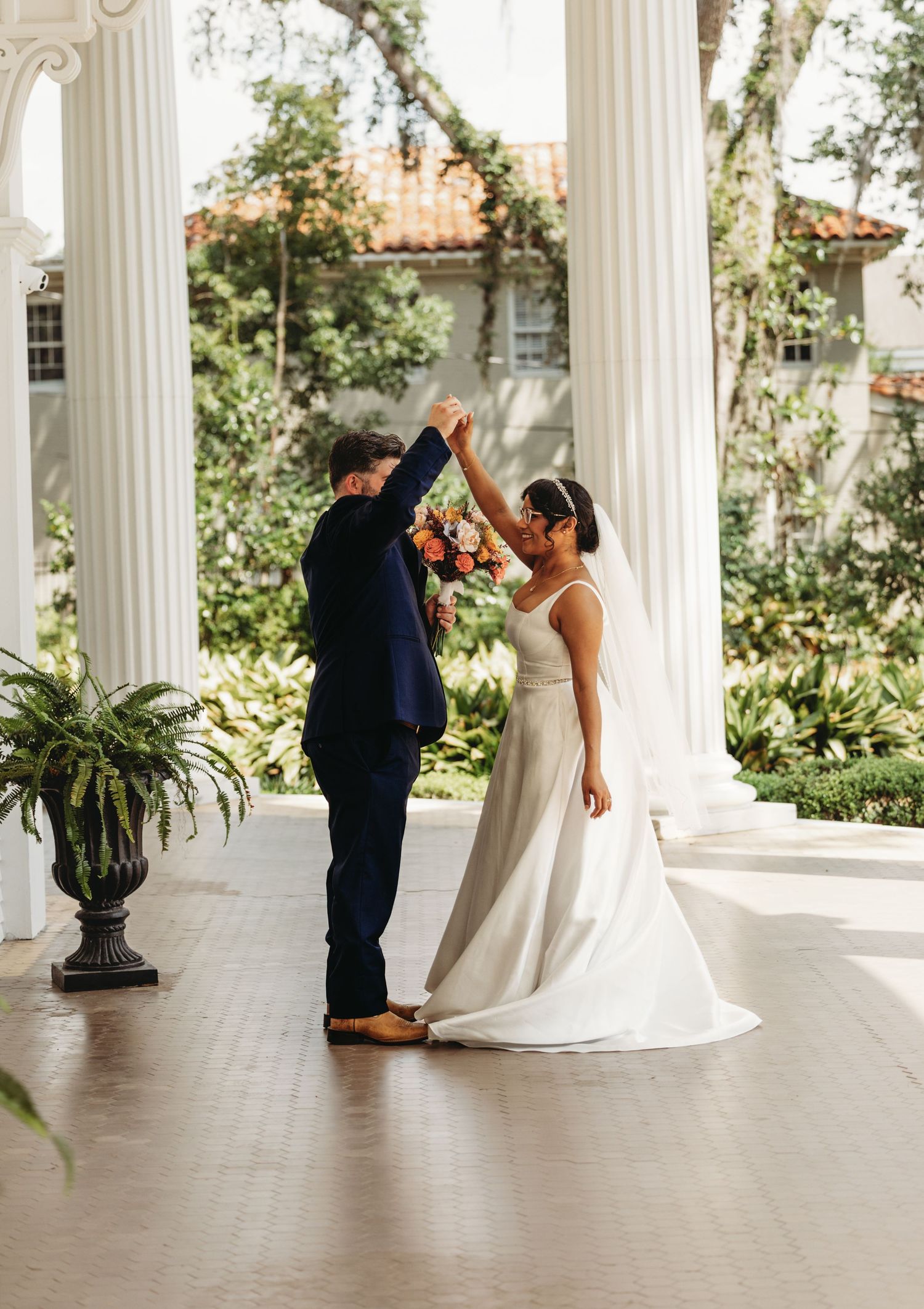 Wedding couple shares intimate moments on an elegant columned veranda.
