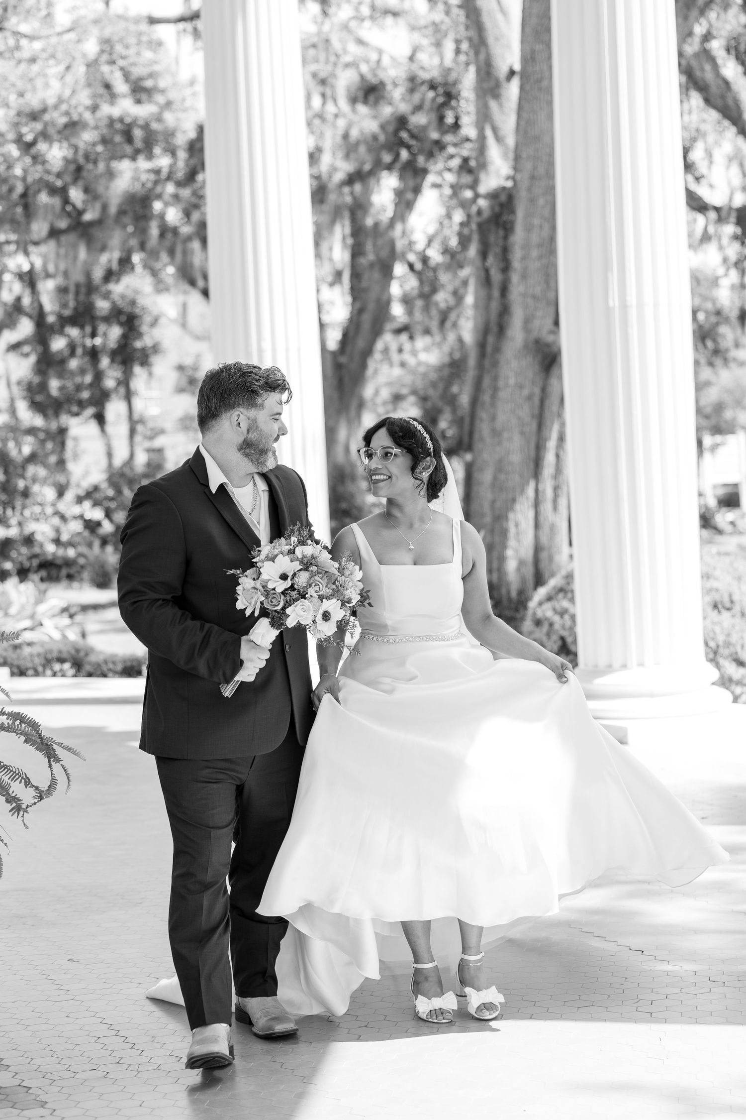 Black and white sequence of wedding couple posing under white columns outdoors.