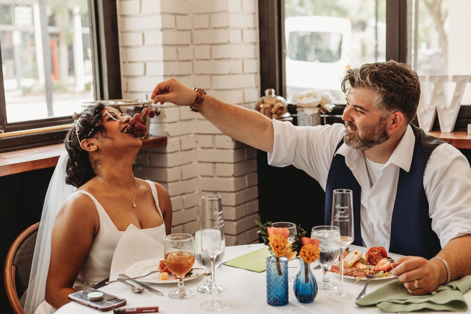 Wedding party enjoying drinks and food at a casual reception with brick walls.