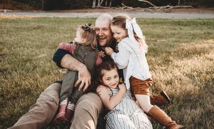 A heartwarming family scene with loving embraces on a grassy field at golden hour.