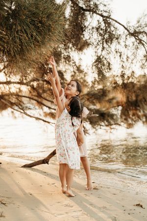 A playful sequence of images shows a person dancing on a sandy beach under overhanging trees at sunset.