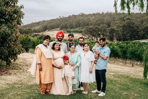 Wedding party walking along grassy hillside on sunny day in rustic outdoor venue setting.