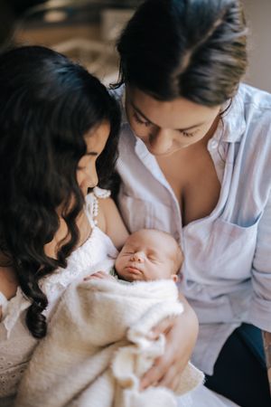 Parent and newborn share intimate bonding moments during feeding time in muted neutral tones.