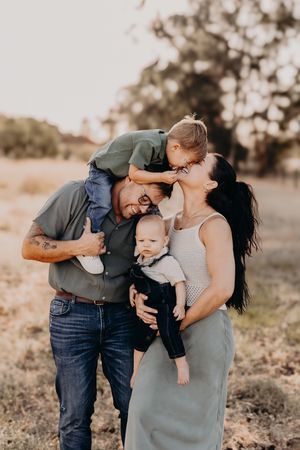 Young family shares joyful moment together outdoors during golden hour sunset in a field.