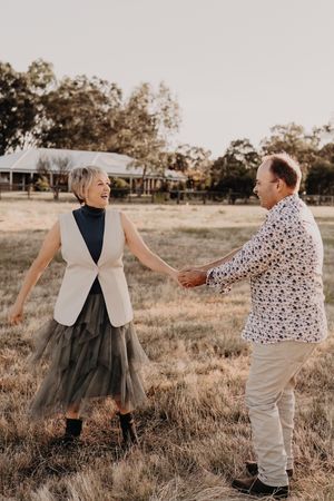 A couple dances together in a field at golden hour, with the woman wearing a black and white dress.
