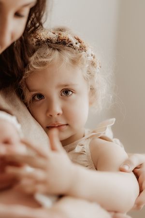 A close-up portrait in warm tones with delicate flowers adorning soft curls, creating an ethereal and tender mood.
