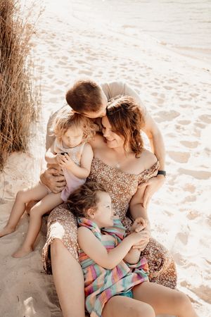 A tender moment shared between parent and child sitting together on a sandy beach at sunset.