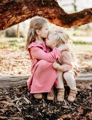 A sequence of natural autumn outdoor shots shows someone sitting on a fallen log amid brown leaves in pink clothing.
