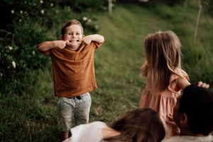 Children playing and laughing together on a grassy hill during a warm summer day.