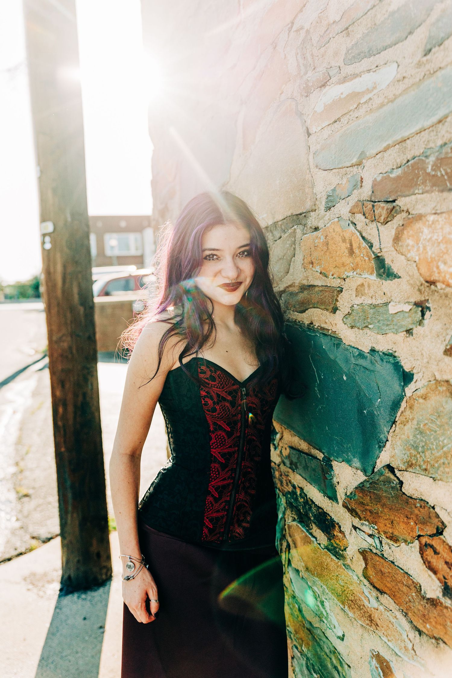 Figure in a black outfit poses against a textured stone wall in artistic multiple exposure photos.
