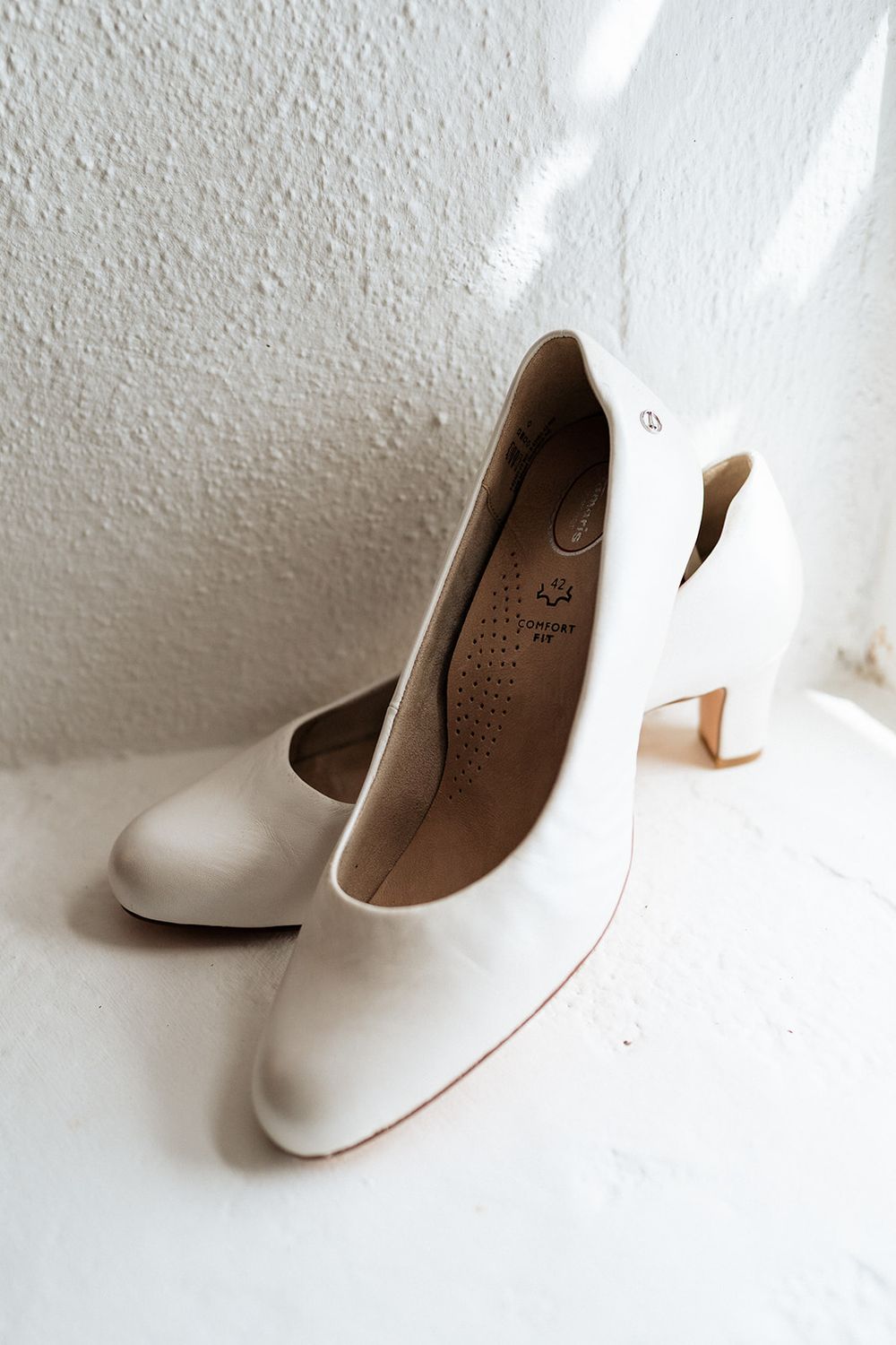 A sequence of minimalist photos showing different angles of a classic white high heel shoe on a white background.
