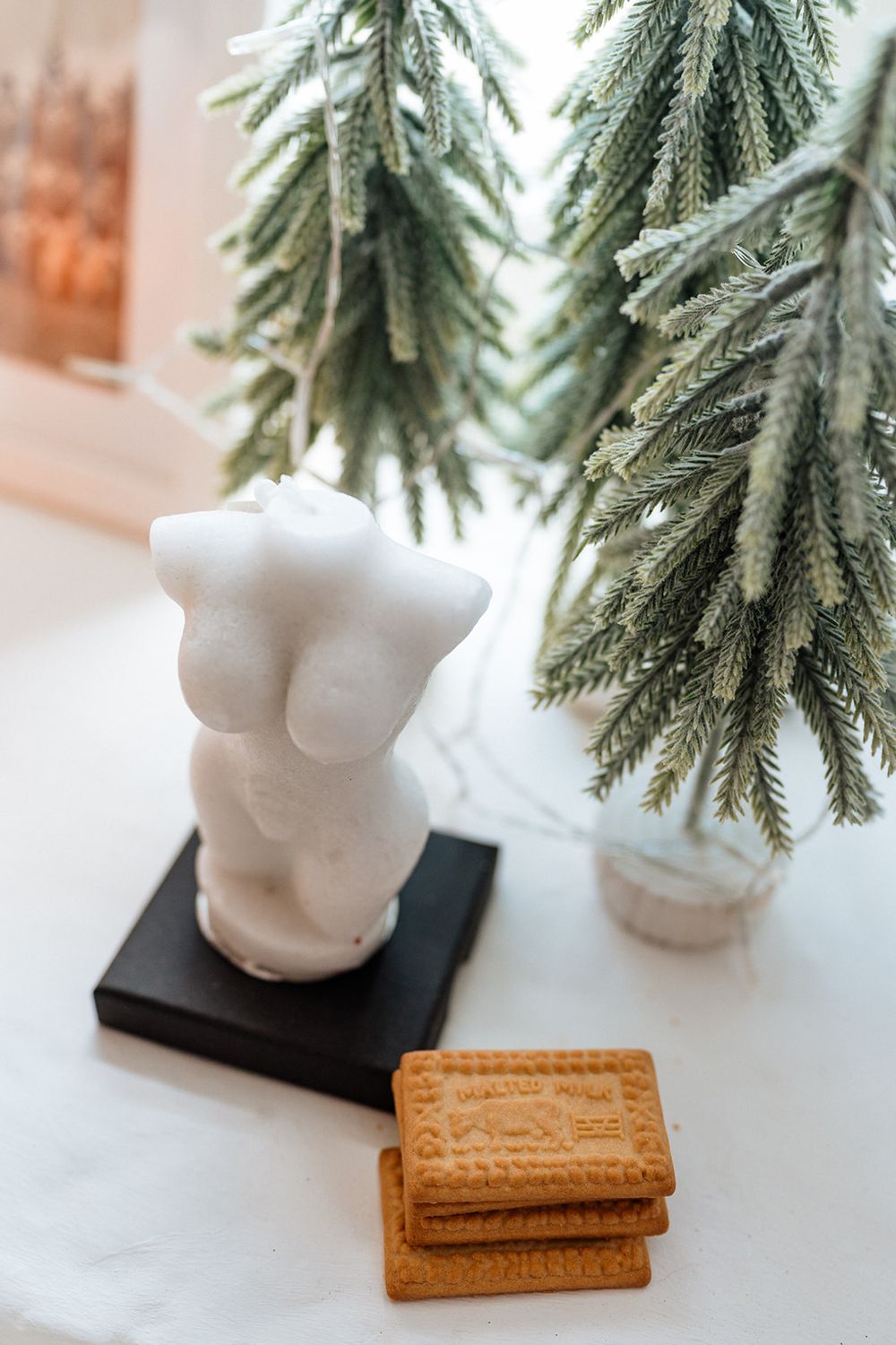 Festive holiday decor featuring white ceramic owl figurines next to golden butter cookies beneath evergreen branches.