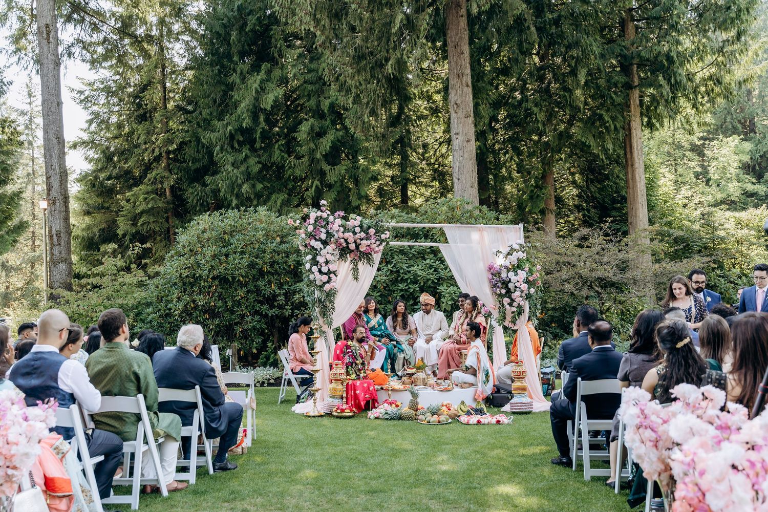 Panoramic view of an outdoor wedding ceremony setup with white chairs and floral decorations.