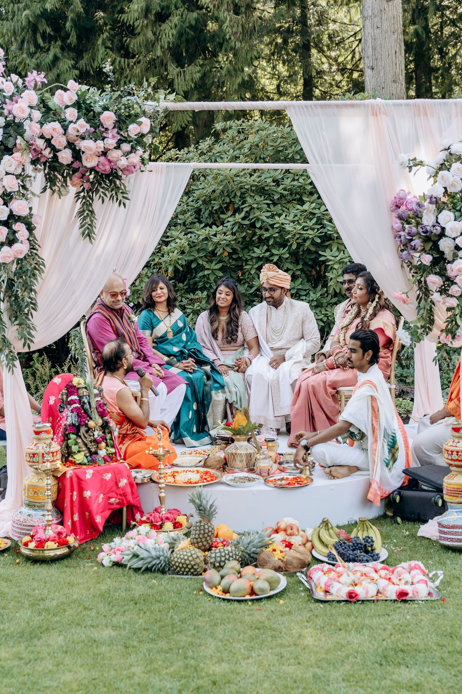 Traditional Indian wedding ceremony setup outdoors with white drapes and colorful guests enjoying a feast.