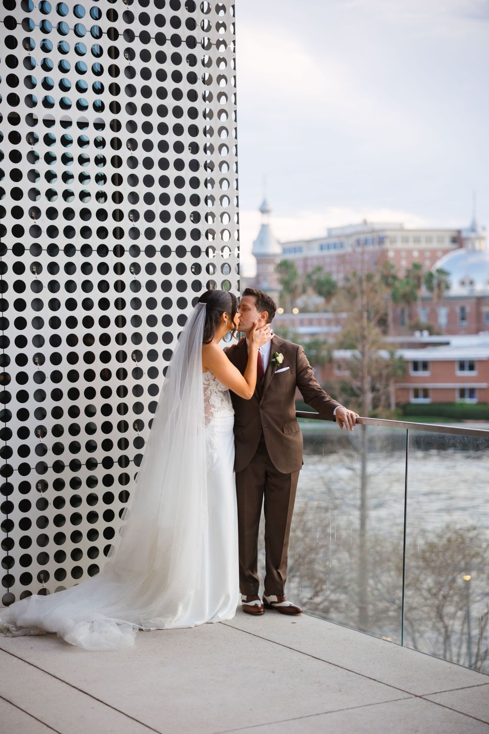 Artistic wedding shoot against a polka dot wall with water and cityscape backdrop.