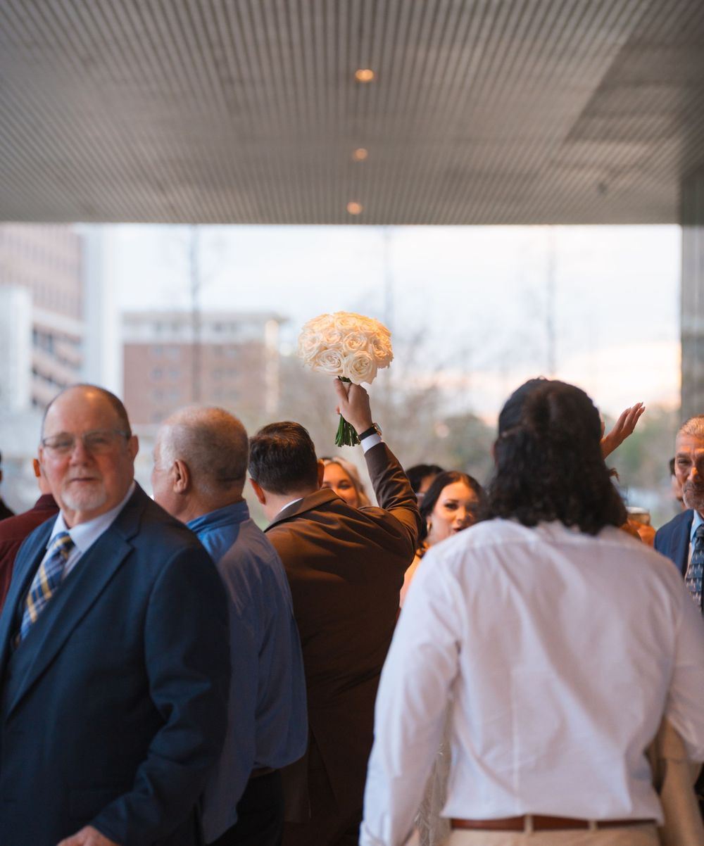 A group of wedding guests gathered at an indoor reception venue with LED ceiling lights.