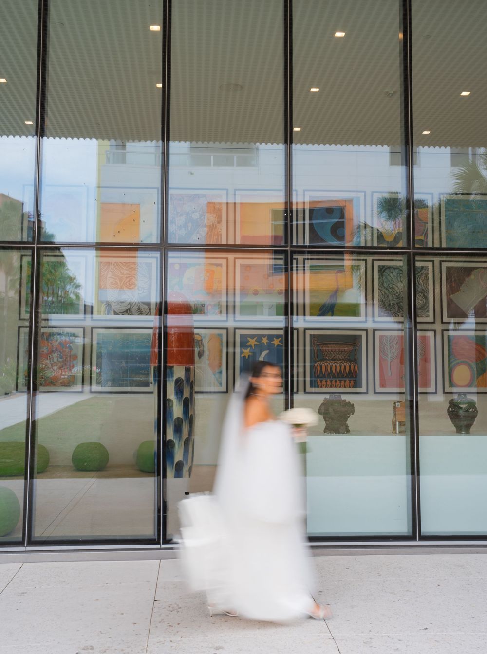Long exposure wedding photography captures ethereal movement across glass building entrance.