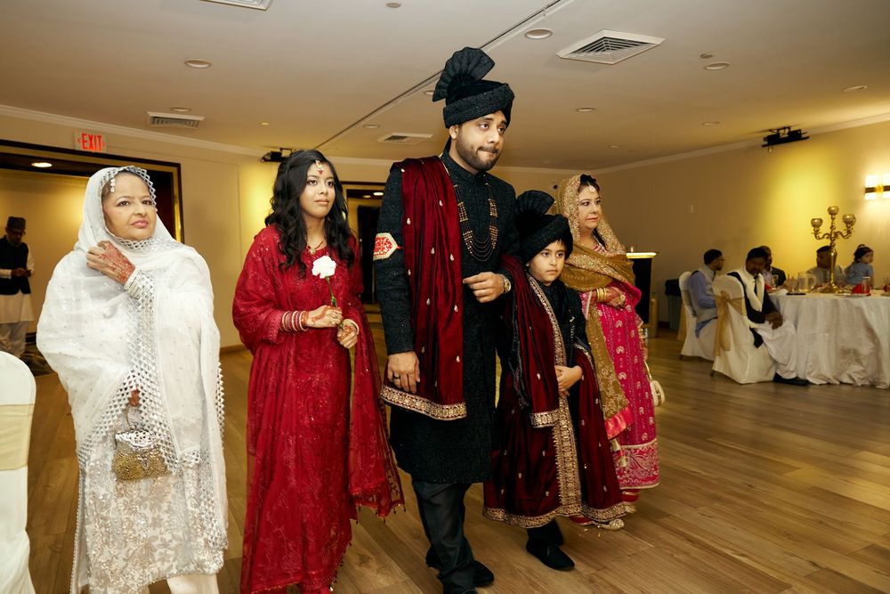 People dressed in traditional South Asian formal attire stand in a line at a festive event in a banquet hall. at Antuns by Minar