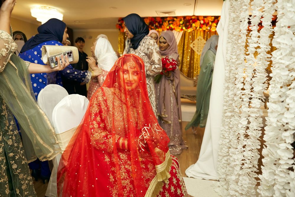 Traditional wedding celebration with a bride in vibrant red bridal attire with gold embellishments and veil. at Antuns by Minar