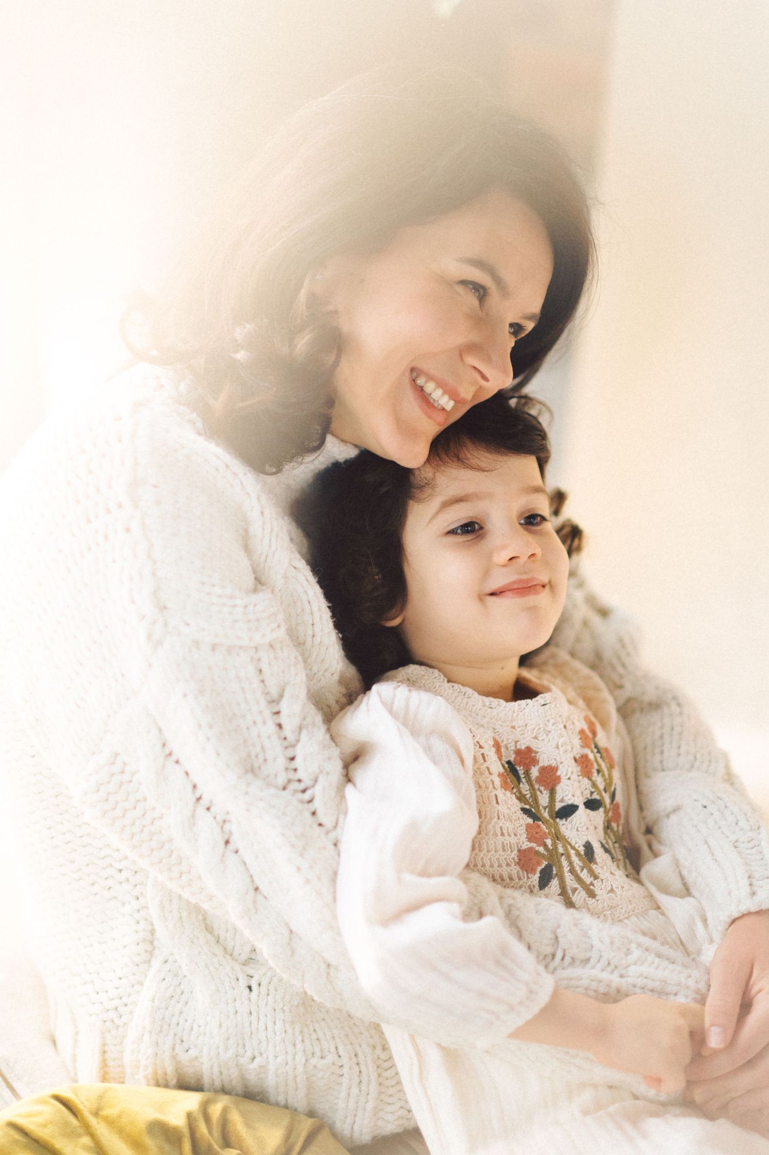 A joyful family scene in soft lighting shows tender embraces and warm white knit clothing in a comforting sequence.