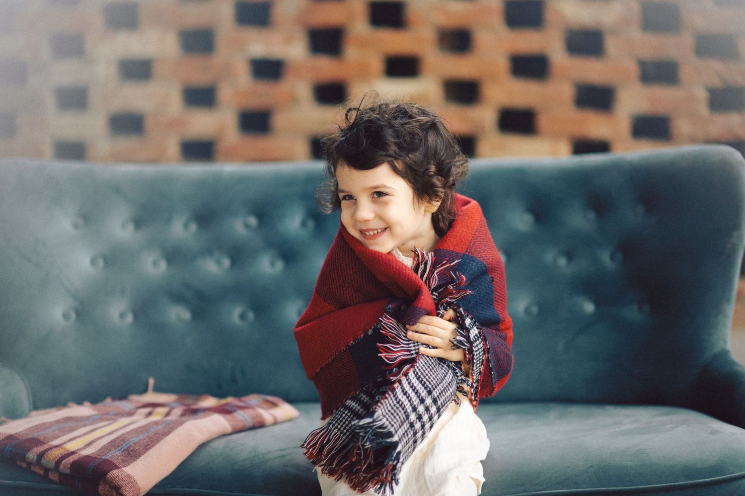 Young person in red sweater lying on teal couch showing various resting positions.