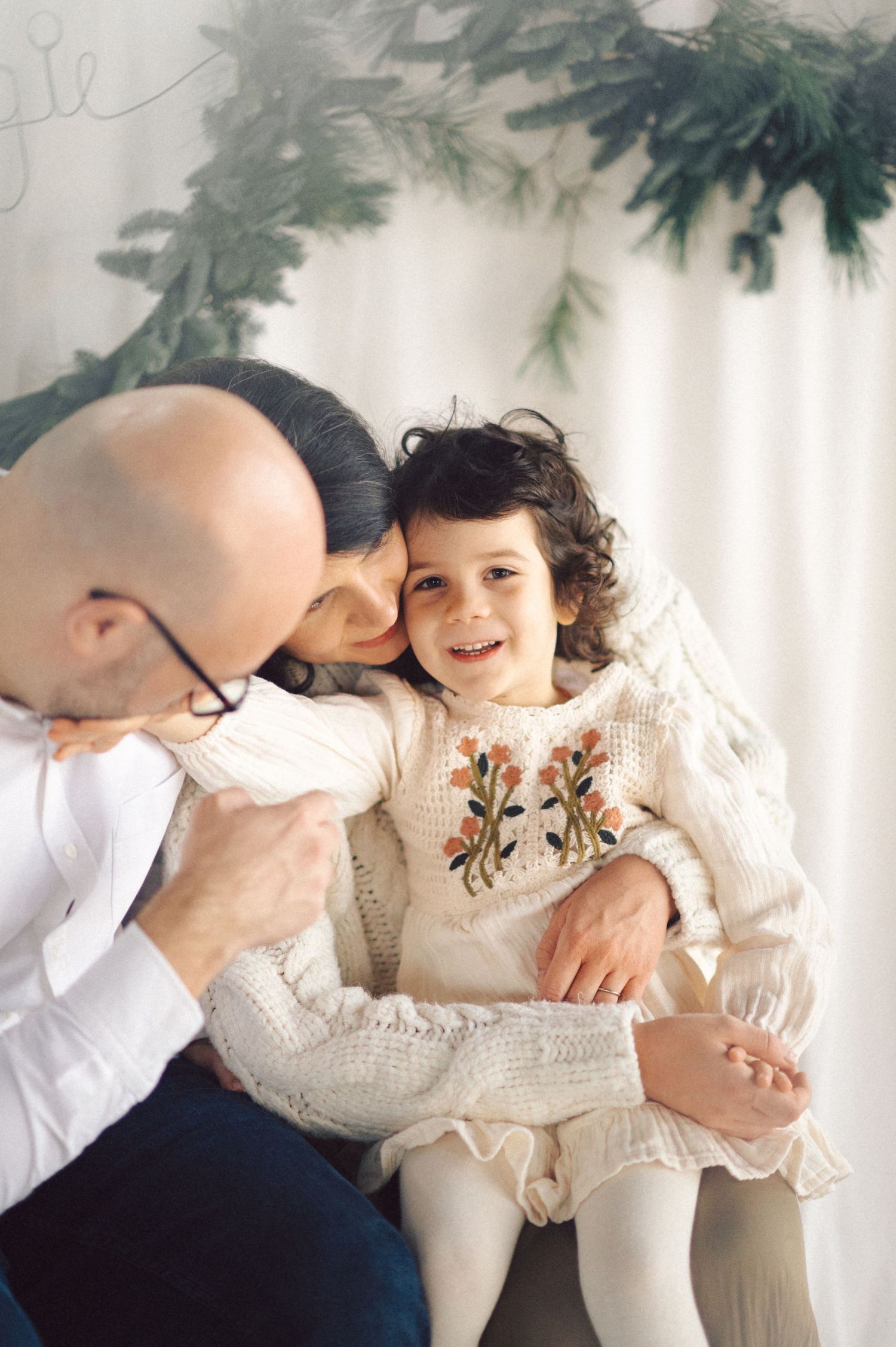 Intimate family portrait series showing tender moments between relatives against a white backdrop with soft natural lighting.