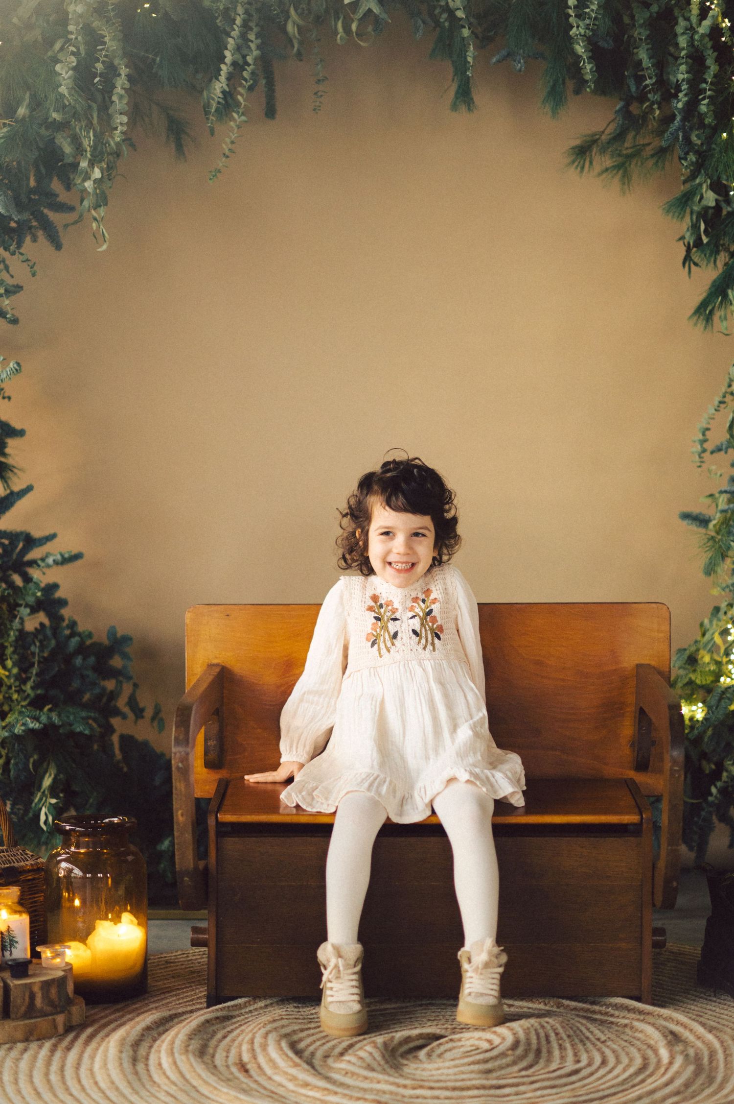 A sequence of playful poses on a wooden bench with evergreen decorations and candlelight.