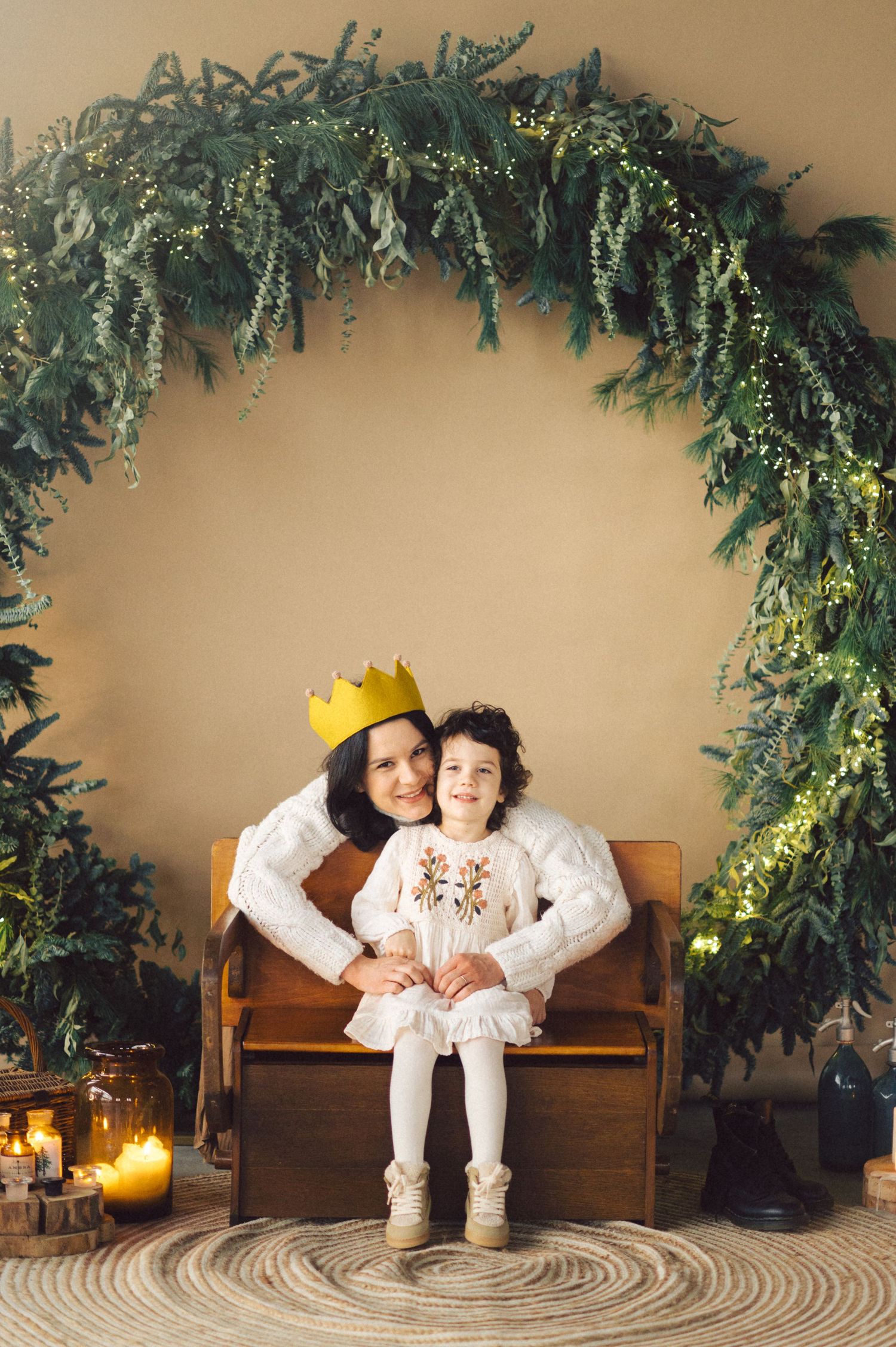 A cozy indoor photoshoot with festive decorations featuring candlelit ambiance and pine garlands.
