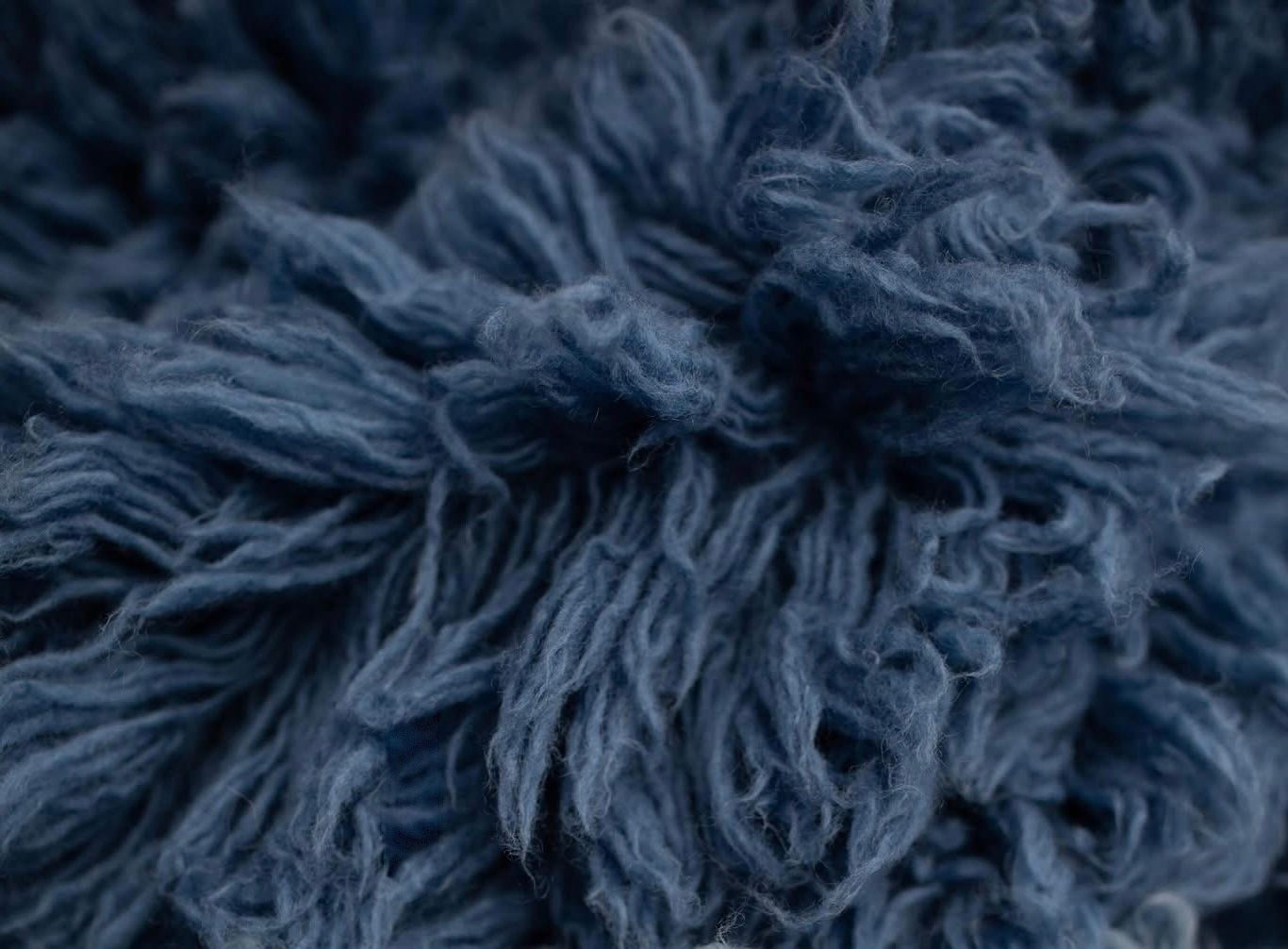 A plush lavender faux fur rug with long shaggy texture on wooden flooring.