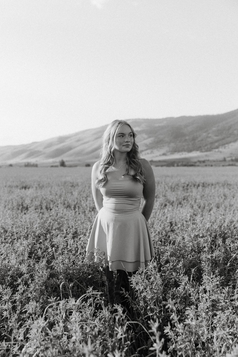 Black and white portrait in a wildflower field with mountains in the distance.