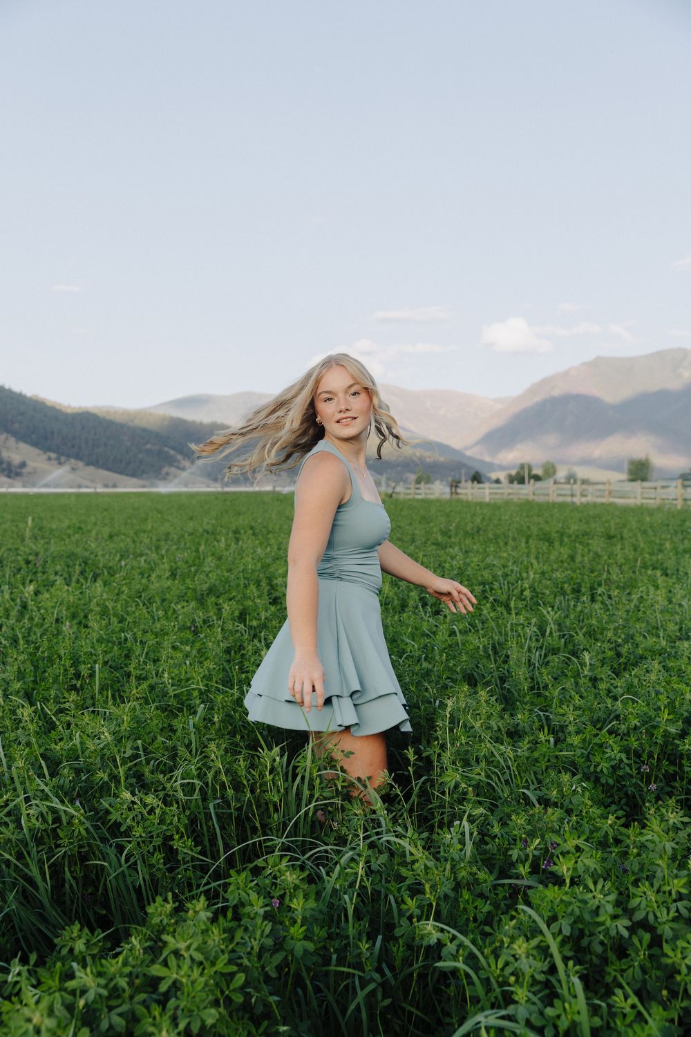 A playful outdoor photoshoot in a lush green agricultural field with mountains on the horizon.