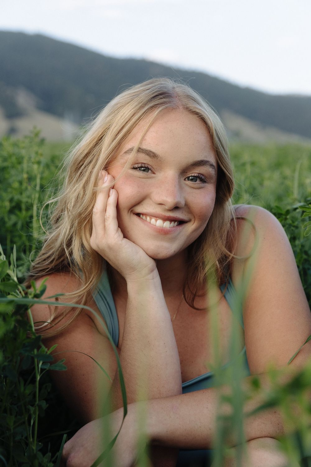 Candid portrait session in a lush green field with mountains in the background.