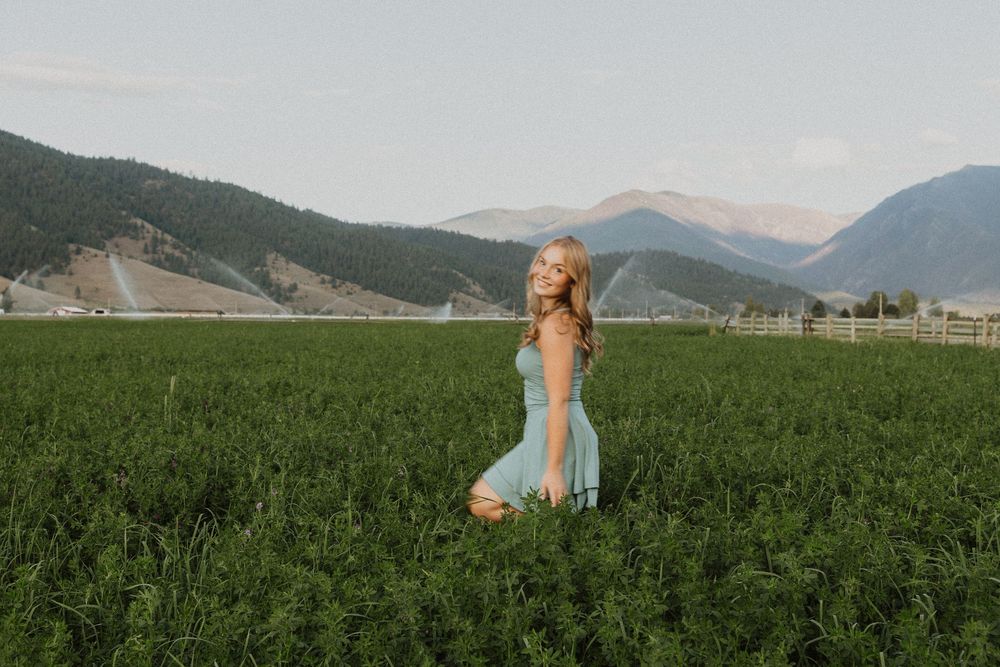 Summer photoshoot in a sprawling green field with mountain landscapes.
