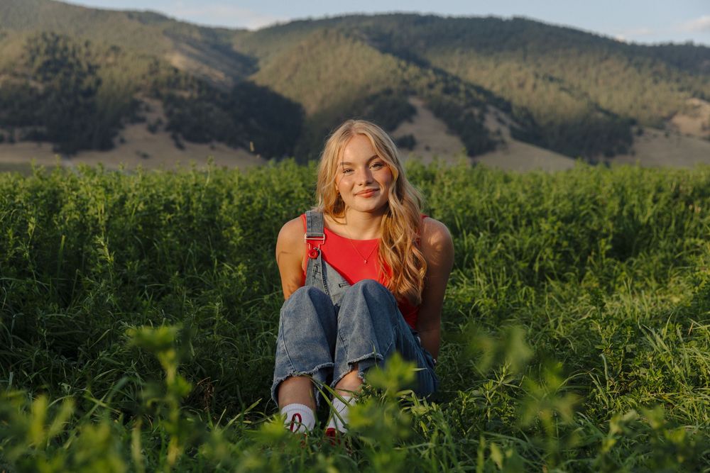 Outdoor photography session in a rural field with mountainous backdrop.