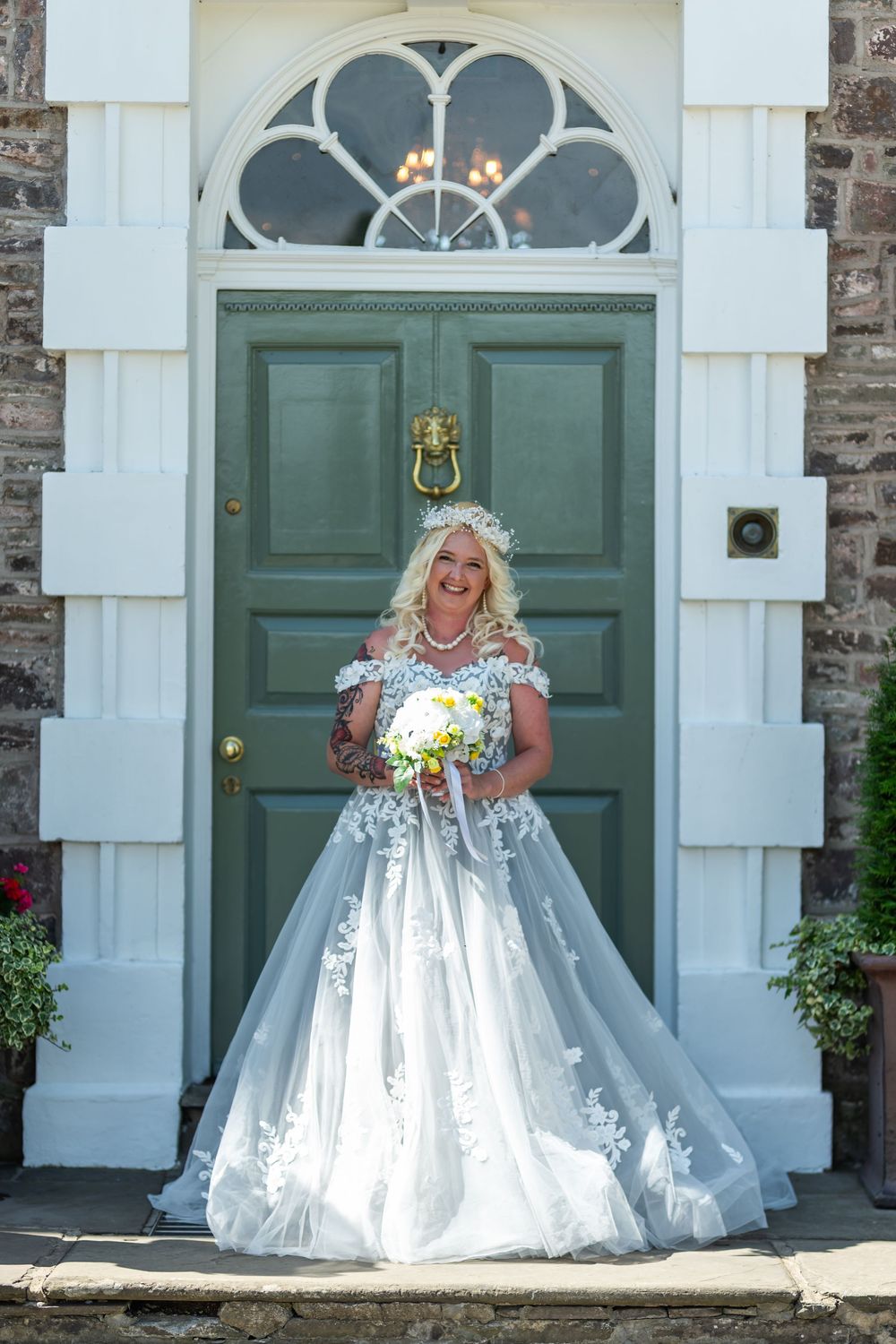 White wedding gowns and floral bouquets displayed in front of vintage green doors with classic architectural details.