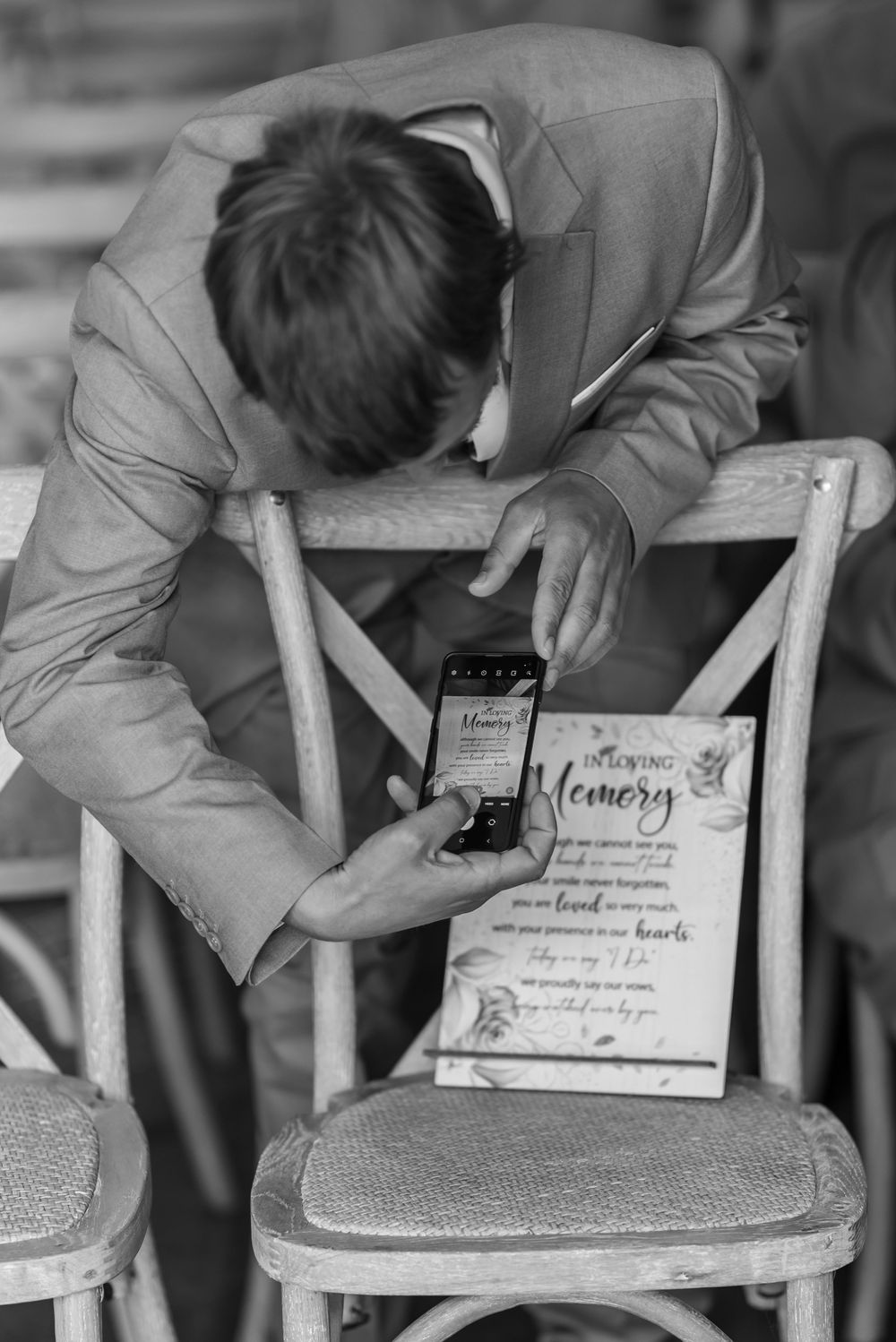 Person signing wedding certificate on white wooden chair.