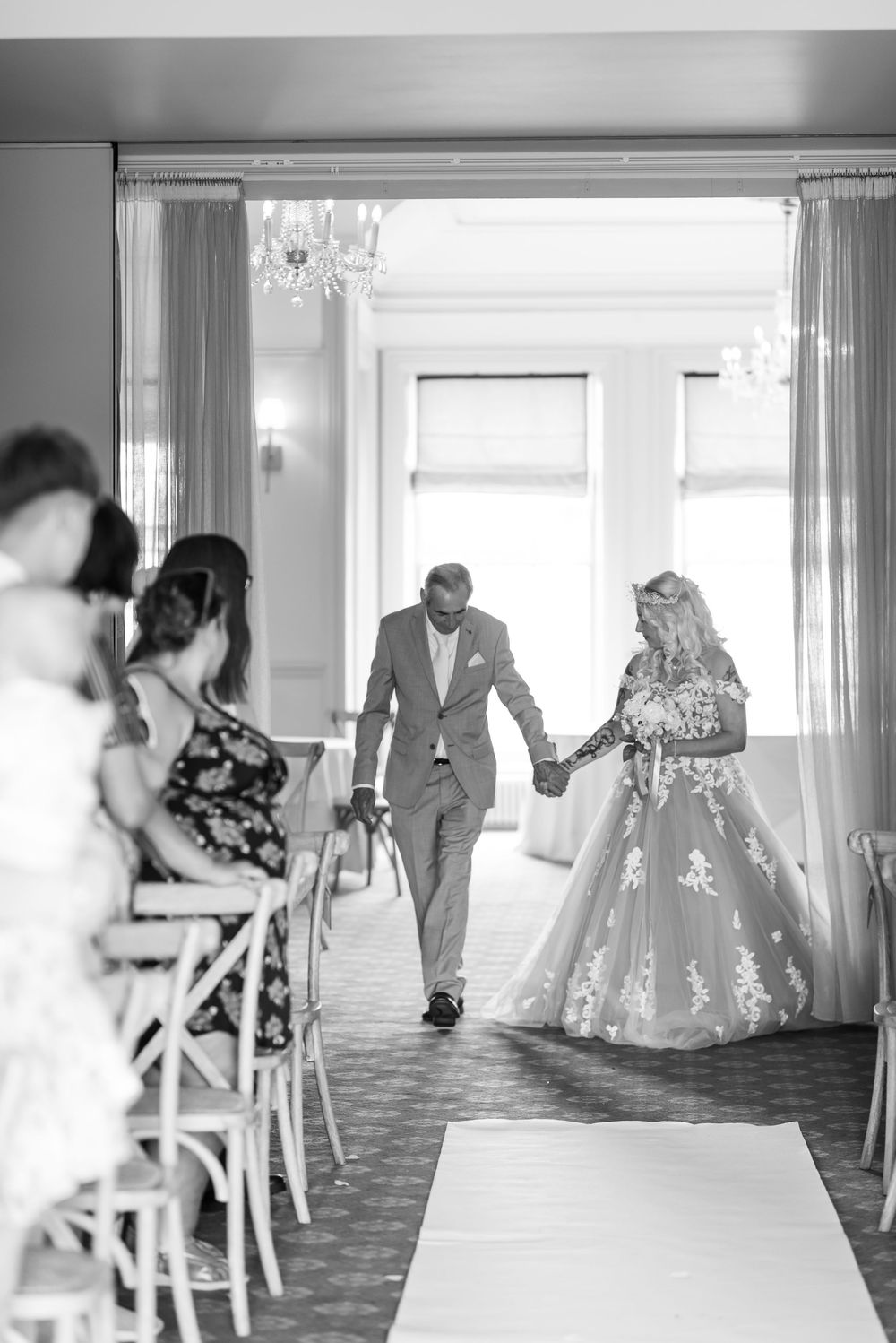 Wedding ceremony setup in an elegant white room with chairs and natural lighting.