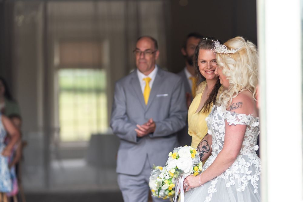 Wedding party members in gray suits and formal attire gather indoors for celebration photos.