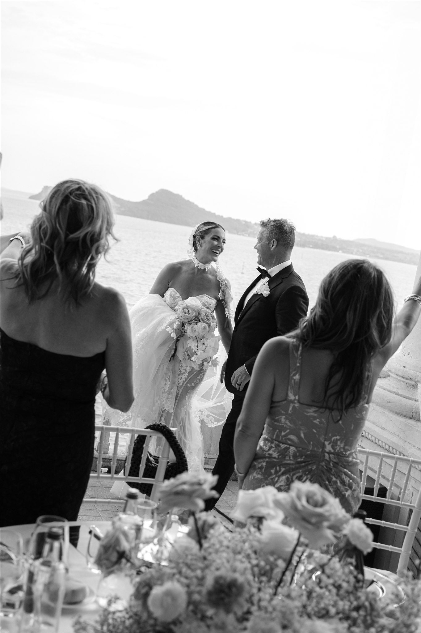 Black and white wedding reception scene with guests mingling around decorated tables.