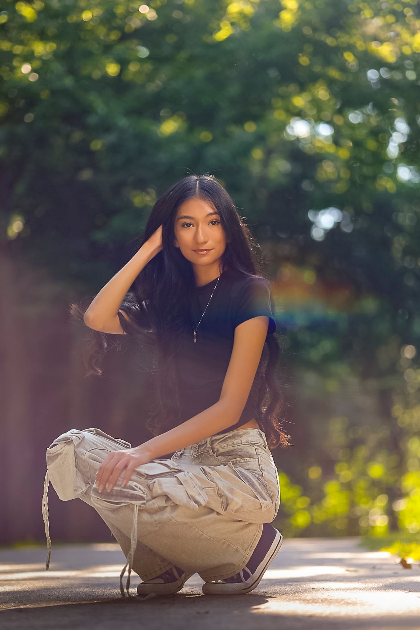 A woman in casual attire sits on a wooden bench in a sunlit outdoor setting with bokeh background effects at Gulley Park