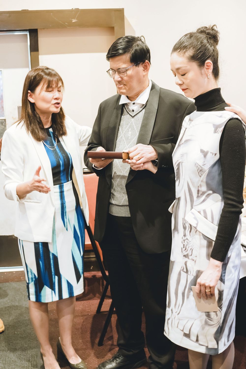 A group of people examining and discussing white lab coats and clothing at an indoor event or gathering.