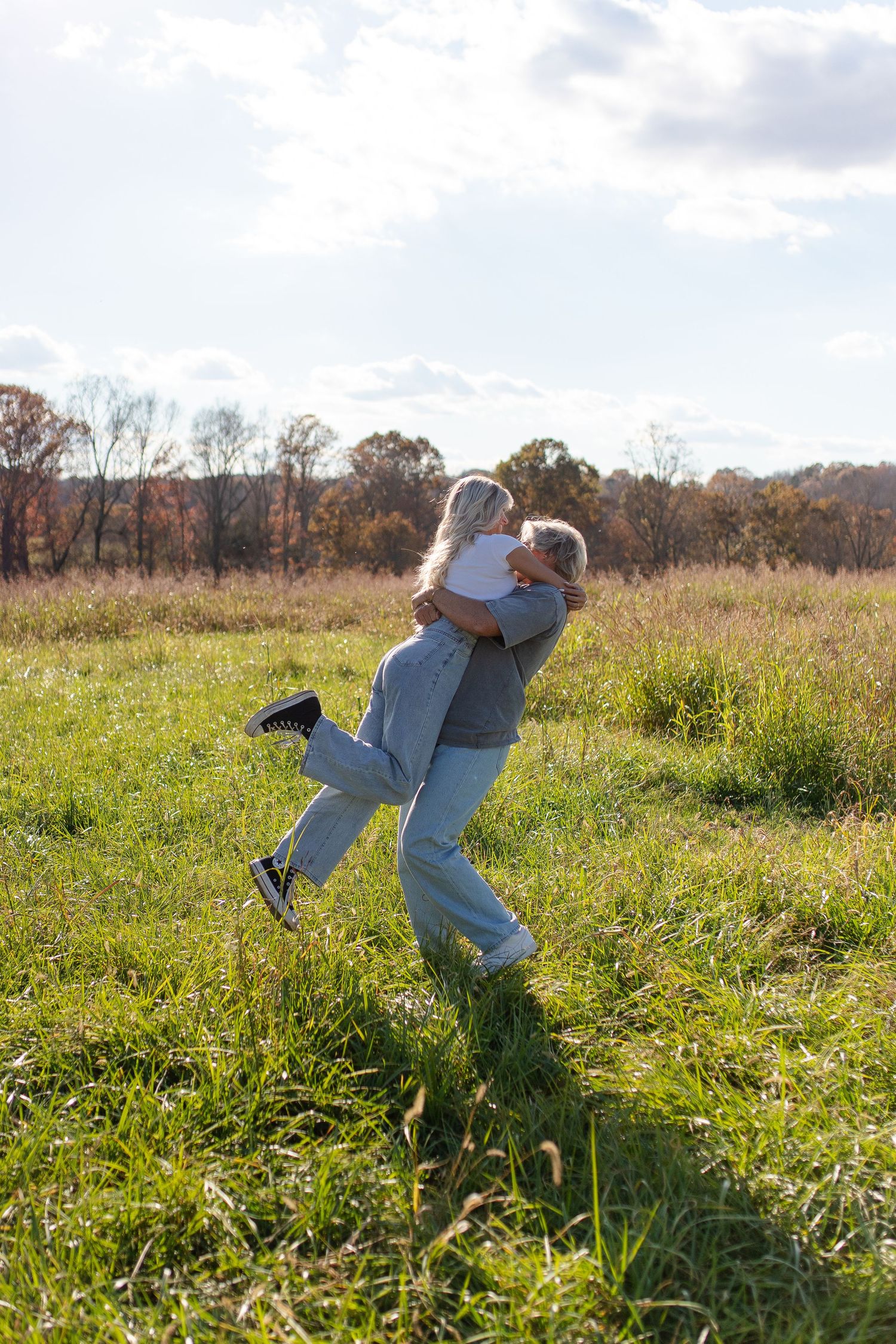 Playful couple photos spinning and dancing in a sunny field.