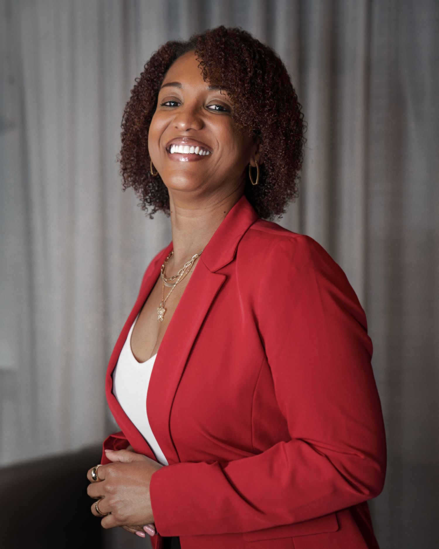 Confident professional portrait in red blazer and white top against light background.