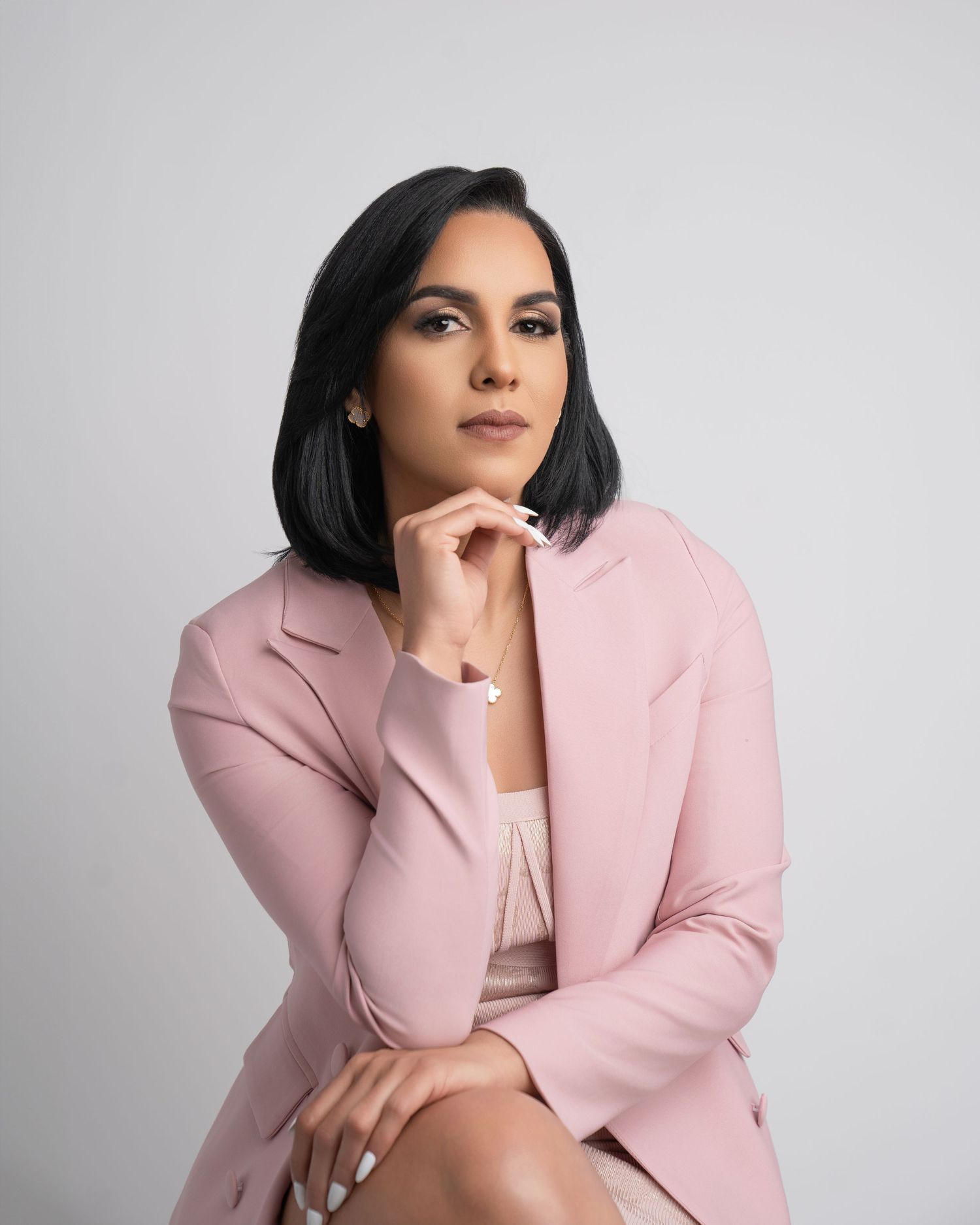 Professional portrait in pink blazer against light gray background.