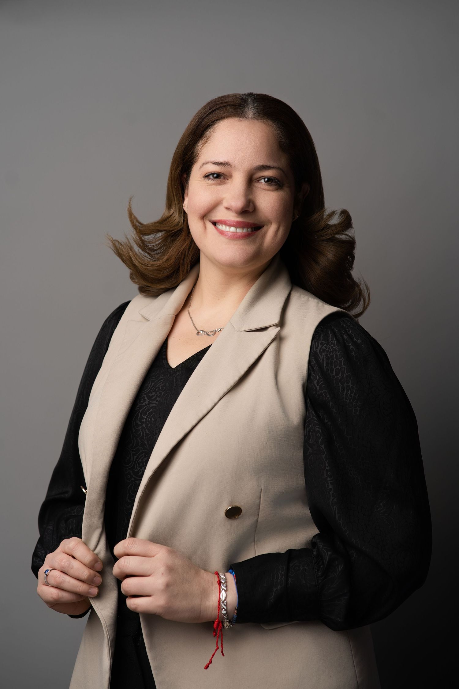 Professional headshot featuring beige and black color block blazer with warm expression.