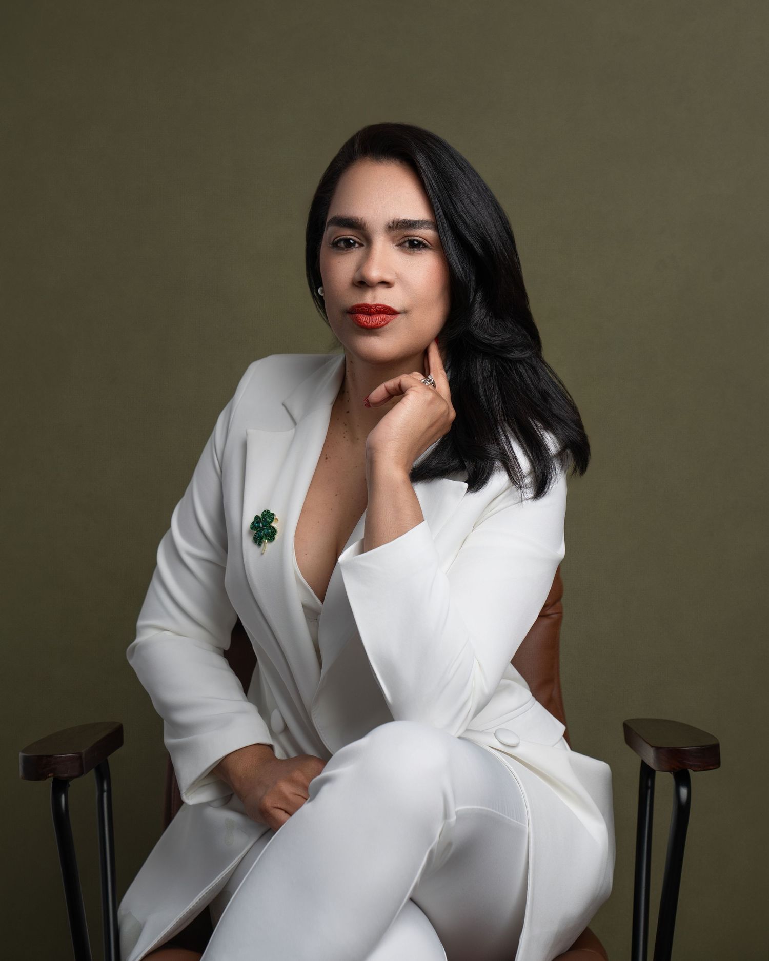 Professional portrait featuring white pantsuit against dark background.