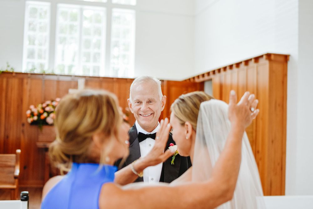 Wedding guests share a joyful moment during a celebration in a church venue with wooden paneling.