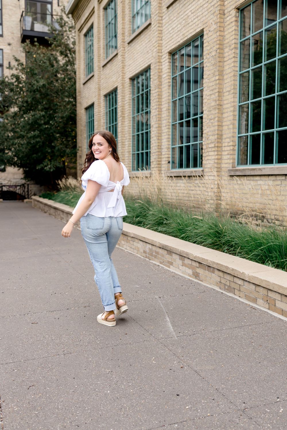 Dynamic walking poses along brick building with large windows.