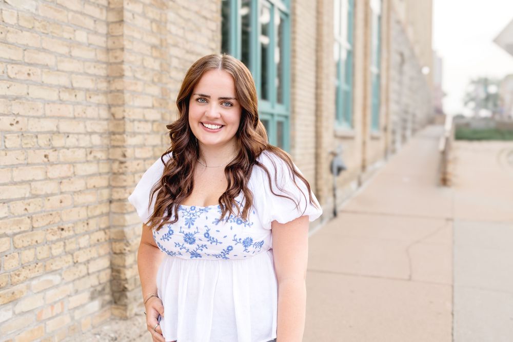 Casual outdoor portrait against architectural backdrop with turquoise accents.