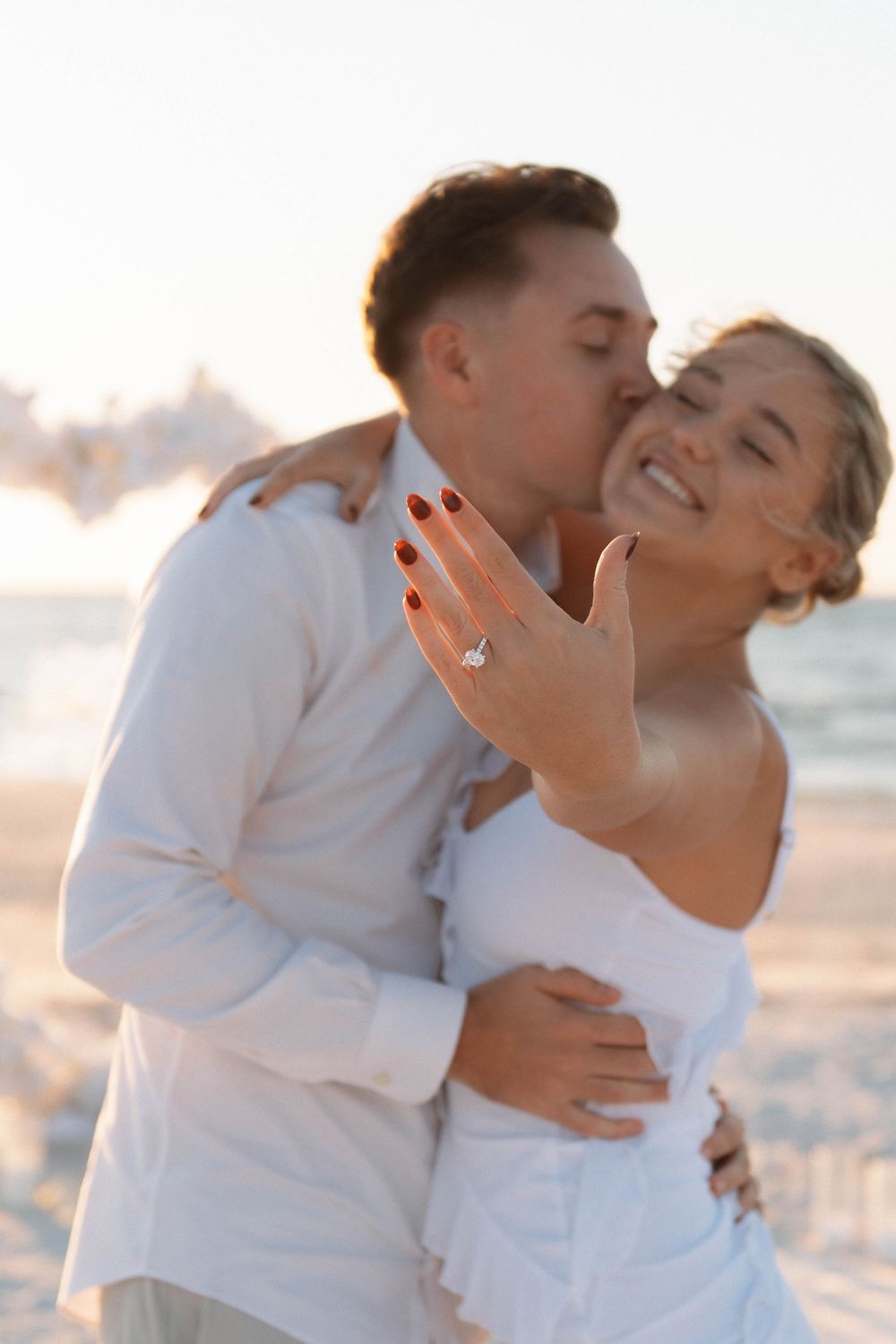Beach proposal beneath a white heart arch on Honeymoon Island, Florida engagement photography.